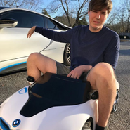 MrBeast next to a car while riding a toy version of the car.