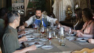 Karl holding Tobias' right hand at the dining table